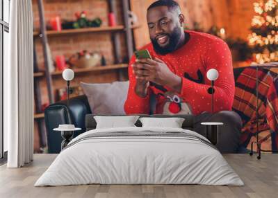 Photo of young black man happy positive smile look read browse cellphone post blogger x-mas noel indoors Wall mural