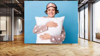 Photo of young cheerful girl happy positive smile dream embrace pillow cozy comfort isolated over blue color background Wall mural