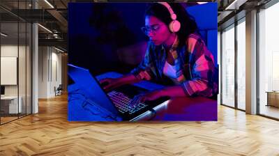 Photo of young concentrated woman play gaming laptop esport neon light night apartment indoors Wall mural