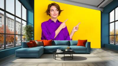 Photo of young consultant woman wear violet shirt direct fingers empty space tips for your business isolated on yellow color background Wall mural