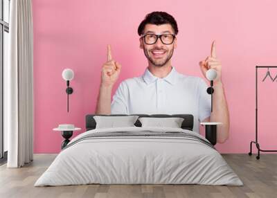 Photo of young funny excited positive handsome bearded man wear eyeglasses pointing fingers up look new information isolated on pink color background Wall mural