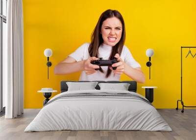 Photo of young girl unhappy play video game joystick angry competition isolated over yellow color background Wall mural