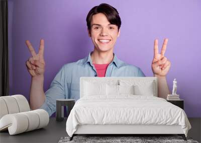 Photo of young guy happy positive smile show peace cool v-sign hello isolated over violet color background Wall mural