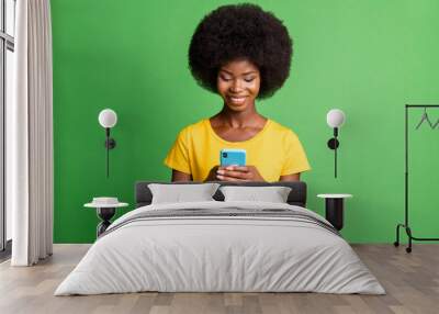 Photo of young happy cheerful good mood afro girl blogger addicted to smartphone isolated on green color background Wall mural