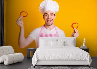 Photo of young happy excited smiling good mood man cook in headwear hold chopped pepper isolated on yellow color background Wall mural