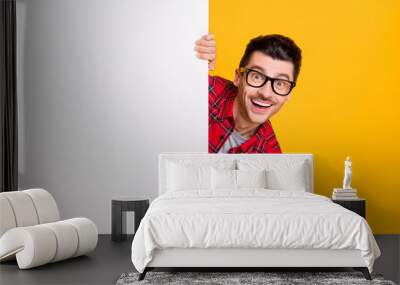 Photo of young happy positive good mood man in glasses hold big white banner isolated on yellow color background Wall mural