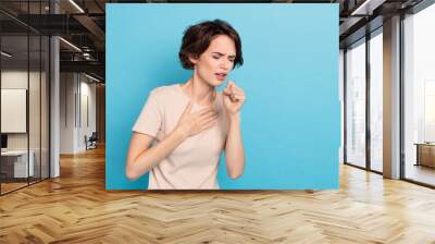 Photo of young lady have covid 19 touch her chest coughing sneezing feel bad isolated on blue color background Wall mural