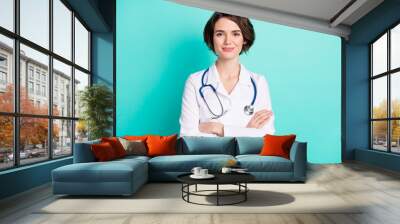 Photo of young woman happy positive smile folded hands intern medic isolated over teal color background Wall mural