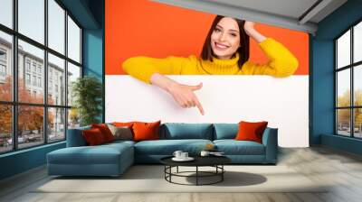 Photo of young woman happy positive smile point finger empty space poster ad promo choose isolated over orange color background Wall mural