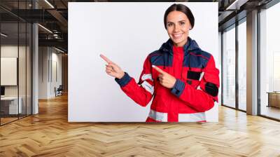 Photo of young woman paramedic happy positive smile indicate fingers empty space ad promo advice isolated over white color background Wall mural