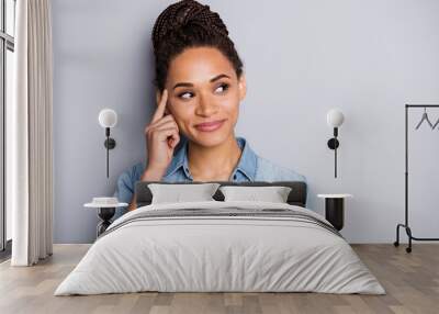 Photo portrait of african american woman touching temple with finger looking at blank space isolated on clear grey colored background Wall mural