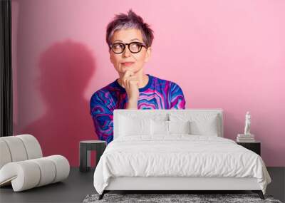 Photo portrait of attractive senior woman thoughtful look empty space dressed blue colorful clothes isolated on pink color background Wall mural