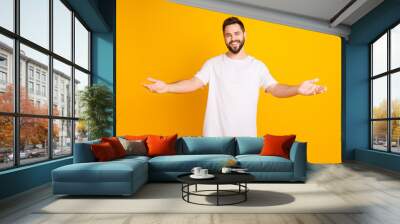 Photo portrait of attractive young man stretch hands want embrace hi dressed stylish white clothes isolated on yellow color background Wall mural