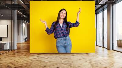 Photo portrait of attractive young woman raise hands dressed stylish plaid clothes isolated on yellow color background Wall mural