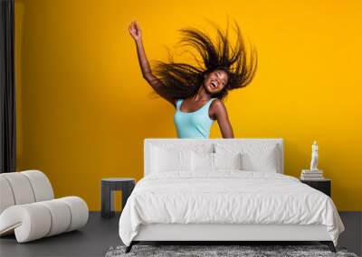 Photo portrait of cute active african american girl dancing with one hand in air hair flying wearing blue mini dress isolated on vivid yellow colored background Wall mural