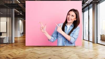 Photo portrait of female student showing finger looking empty space advising isolated on pastel pink color background Wall mural