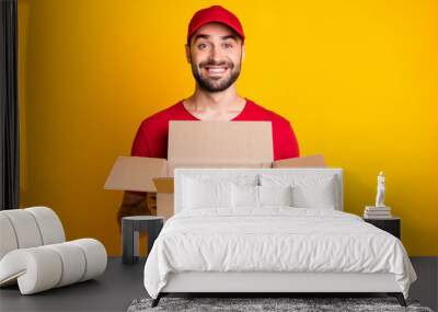 Photo portrait of funny courier keeping opened box for belongings packing smiling isolated on bright yellow color background Wall mural