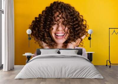 Photo portrait of girl with curly hairstyle wearing t-shirt laughing touching hair isolated on bright yellow color background Wall mural