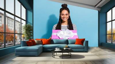 Photo portrait of girl with dreadlocks cheerful keeping wrapped present box at party isolated pastel blue color background Wall mural