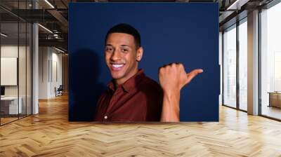 Photo portrait of handsome young man point empty space dressed stylish brown garment isolated on dark blue color background Wall mural