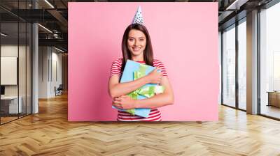 Photo portrait of happy birthday girl hugging wrapped gift wearing festive cone isolated on pastel pink color background Wall mural