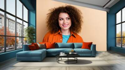 Photo portrait of lovely young lady look interested empty space dressed stylish orange garment isolated on beige color background Wall mural