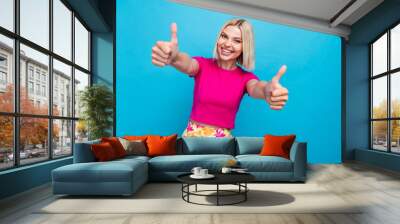 Photo portrait of lovely young lady show thumbs up dressed stylish pink clothes isolated on blue color background Wall mural