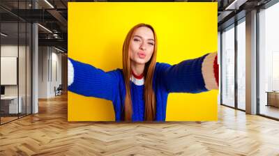 Photo portrait of lovely young lady take selfie kiss pouted lips dressed stylish blue knitwear garment isolated on yellow color background Wall mural