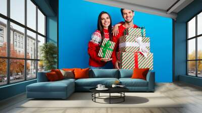 Photo portrait of pretty young lovers presents pile shopping sales dressed x-mas ornament red sweaters isolated on blue color background Wall mural