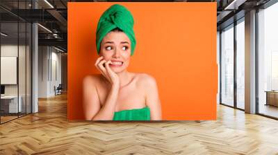 Photo portrait of scared woman biting fingers nails looking at blank space isolated on bright orange colored background Wall mural