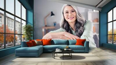 Photo portrait of senior woman wearing glasses grey hair smiling sitting on sofa Wall mural