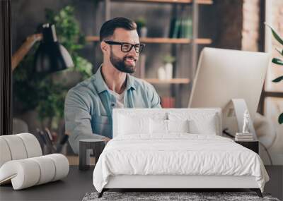 Photo portrait of smiling hipster guy working on desktop pc at table indoors Wall mural