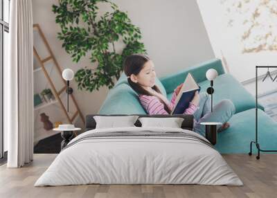 Photo portrait of young funny kid little brunette girl staying at home spending free time sitting divan reading her diary isolated in her room Wall mural