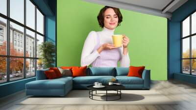 Photo portrait woman smiling smelling coffee aroma isolated pastel green color background Wall mural