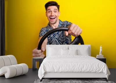 Portrait of astonished positive man arms hold steering wheel open mouth isolated on yellow color background Wall mural