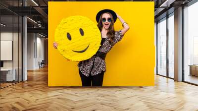 Portrait of attractive amazed cheerful girl holding in hands emoticon wow reaction isolated over bright yellow color background Wall mural