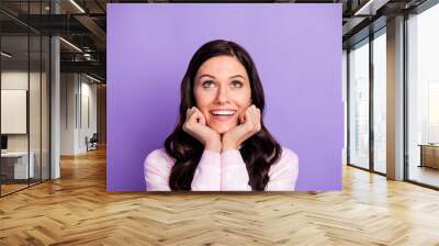 Portrait of attractive amazed cheerful wavy-haired girl looking up copy space ad isolated over violet color background Wall mural