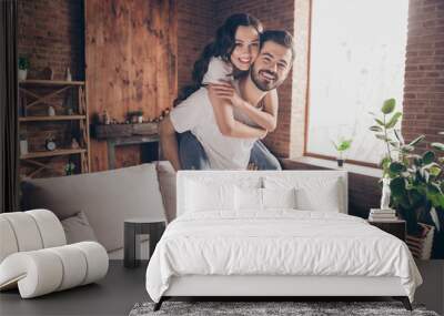 Portrait of attractive careful funny cheerful couple having fun piggy backing spending holiday at loft style interior home house indoor Wall mural