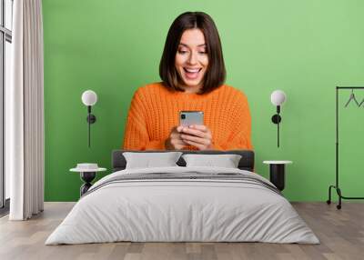 Portrait of attractive cheerful amazed girl using device gadget app smm post isolated over bright green color background Wall mural