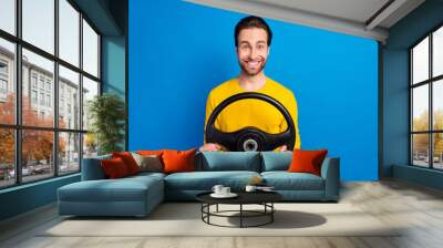 Portrait of attractive cheerful brunet guy holding steering wheel road way isolated over bright blue color background Wall mural