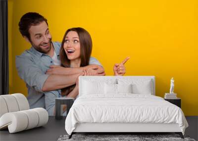 Portrait of attractive cheerful couple hugging showing idea dream copy blank space isolated over bright yellow color background Wall mural