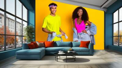 Portrait of attractive cheerful couple wearing retro denim look posing isolated over bright yellow color background Wall mural