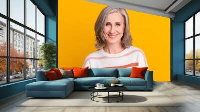 Portrait of attractive cheerful grey-haired woman good mood isolated over vibrant yellow color background Wall mural