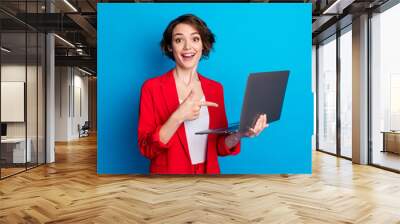 Portrait of attractive cheerful lady freelancer holding in hand laptop showing web education isolated on bright blue color background Wall mural