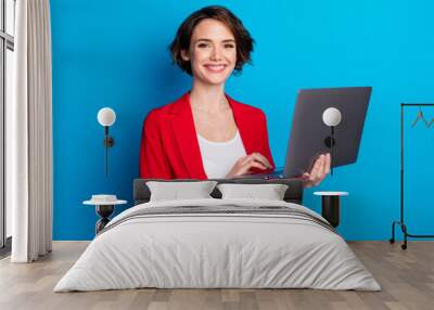 Portrait of attractive cheerful skilled businesslady holding in hand laptop isolated over bright blue color background Wall mural