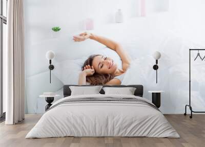 Portrait of attractive lovely girl enjoying time in bad after sleeping lying under blanket making stretching keeping eyes closed. Good day life health concept Wall mural