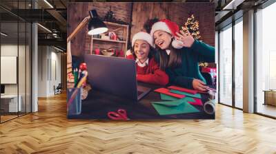 Portrait of cheerful friends preparing event creating advent atmosphere noel using laptop calling waving hello at loft home indoors Wall mural