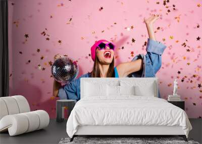 Portrait of cheerful youngster waving her palm screaming shouting wearing blue body suit isolated over pink background Wall mural