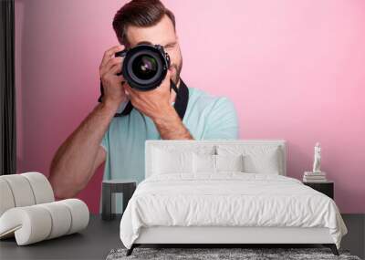 Portrait of concentrated man having summer vacation taking photo with his digital dslr camera wear modern stylish clothes isolated over pink color background Wall mural