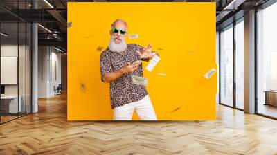 Portrait of crazy funny funky old long bearded man millionaire in eyewear eyeglasses waste money throw banknotes wear leopard shirt shorts isolated over yellow background Wall mural